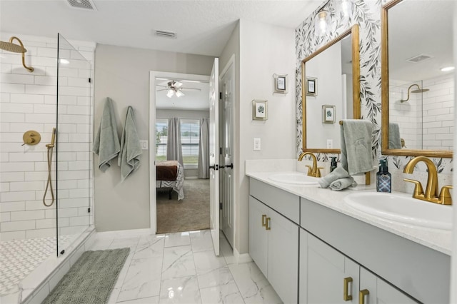 ensuite bathroom featuring baseboards, a ceiling fan, a tile shower, double vanity, and marble look tile flooring