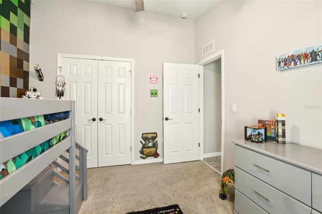 carpeted bedroom with a closet, a high ceiling, and baseboards