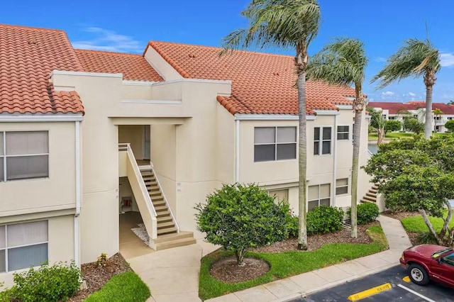view of property with stairs and uncovered parking