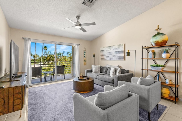 living area with light tile patterned floors, a ceiling fan, and a textured ceiling