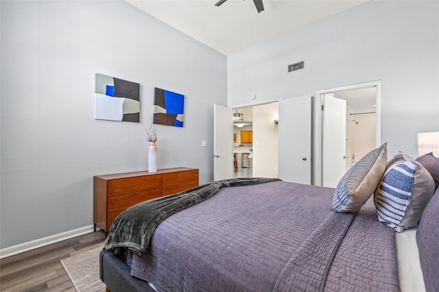 bedroom with wood finished floors, baseboards, a towering ceiling, and a ceiling fan
