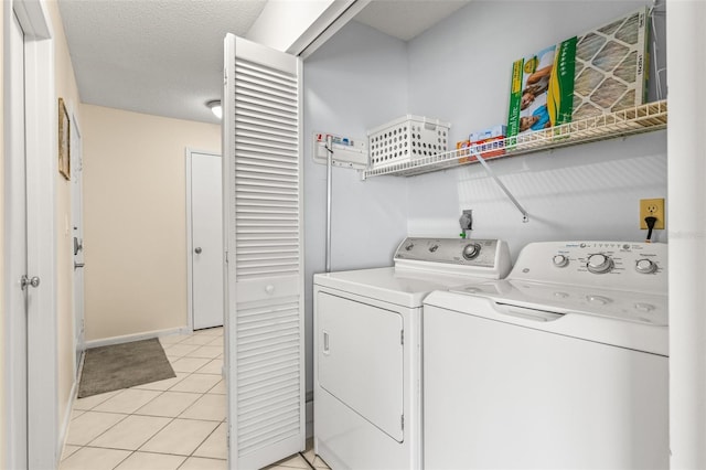 washroom with separate washer and dryer, light tile patterned floors, and baseboards