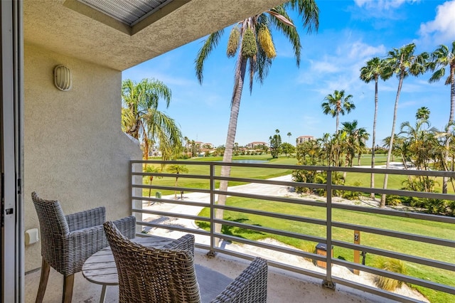 balcony featuring golf course view and a water view