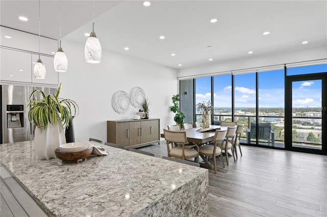 199 Dali Blvd Unit 2, Saint Petersburg, FL 33701 - kitchen featuring recessed lighting, wood finished floors, light stone counters, pendant lighting, and stainless steel fridge with ice dispenser