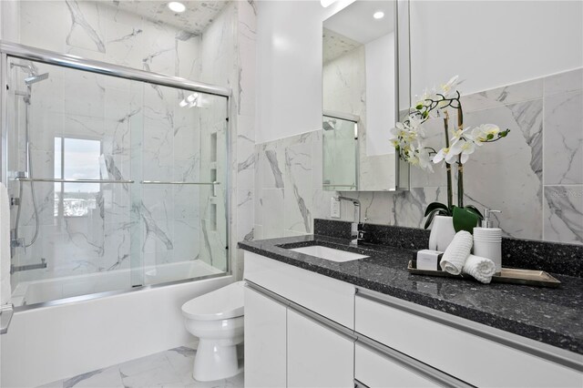 199 Dali Blvd Unit 2, Saint Petersburg, FL 33701 - full bathroom with tile walls, marble look tiles, combined bath / shower with glass door, toilet, and vanity