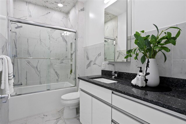 199 Dali Blvd Unit 2, Saint Petersburg, FL 33701 - bathroom with marble finish floors, combined bath / shower with glass door, vanity, toilet, and tile walls