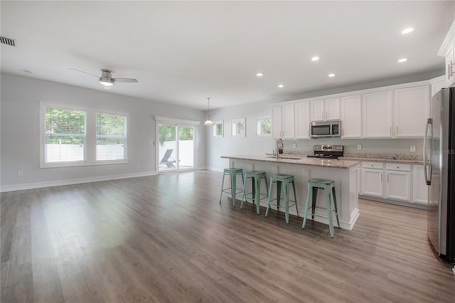 3906 N Lynn Ave, Tampa, FL 33603 - kitchen with stainless steel appliances, a sink, light wood-style floors, white cabinetry, and recessed lighting