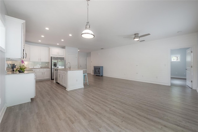 3906 N Lynn Ave, Tampa, FL 33603 - kitchen featuring open floor plan, stainless steel refrigerator with ice dispenser, light wood finished floors, white cabinets, and a sink