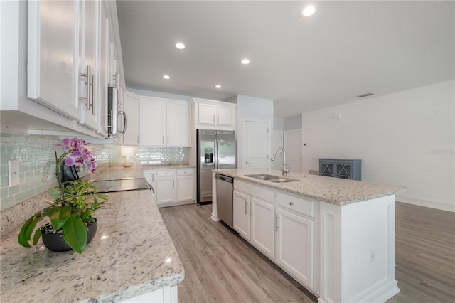 3906 N Lynn Ave, Tampa, FL 33603 - kitchen featuring a sink, appliances with stainless steel finishes, light wood-style flooring, white cabinets, and tasteful backsplash