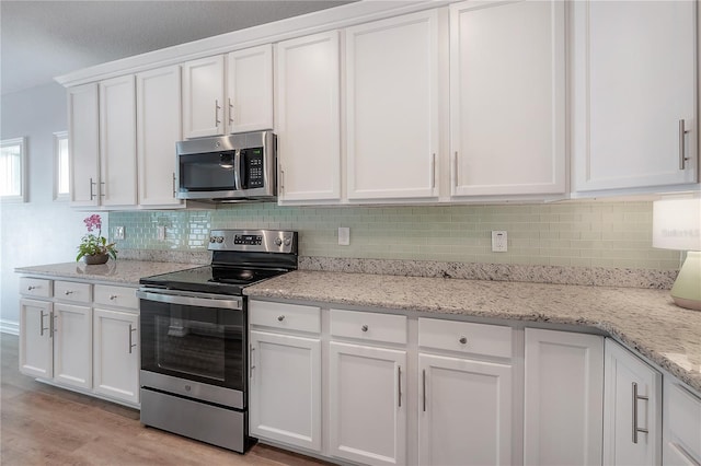 3906 N Lynn Ave, Tampa, FL 33603 - kitchen with stainless steel appliances, white cabinets, backsplash, and light wood finished floors