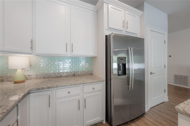 3906 N Lynn Ave, Tampa, FL 33603 - kitchen featuring stainless steel fridge, white cabinets, tasteful backsplash, and light wood-type flooring
