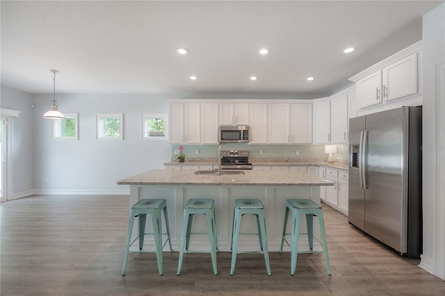 3906 N Lynn Ave, Tampa, FL 33603 - kitchen with stainless steel appliances, a sink, baseboards, a kitchen breakfast bar, and white cabinetry