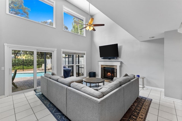 5032 Cypress Trace Dr, Tampa, FL 33624 - living area with light tile patterned flooring, a towering ceiling, ceiling fan, a warm lit fireplace, and healthy amount of natural light