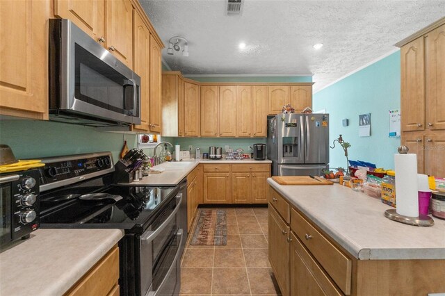 kitchen with appliances with stainless steel finishes, a sink, a textured ceiling, light countertops, and tile patterned floors
