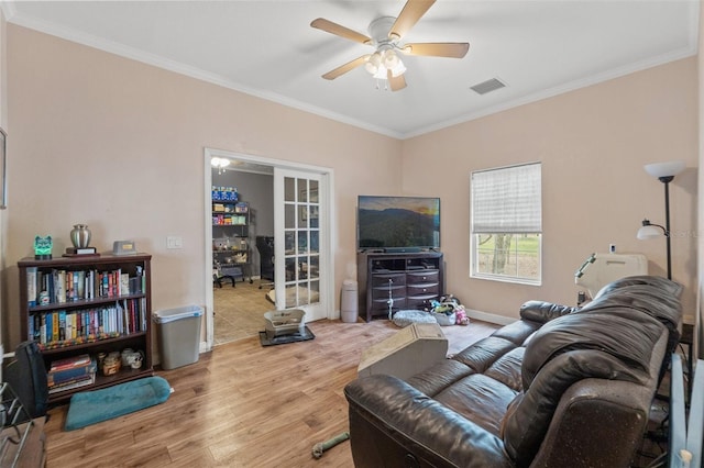 living area with wood finished floors, ornamental molding, ceiling fan, and baseboards
