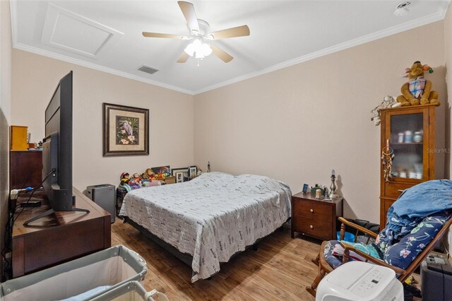 bedroom with wood finished floors, attic access, ornamental molding, and ceiling fan