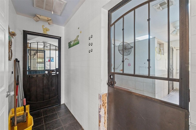 entryway featuring tile walls and dark tile patterned floors