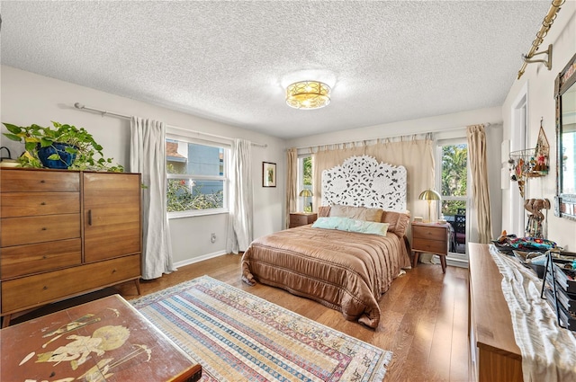 8083 Bayhaven Dr, Seminole, FL 33776 - bedroom featuring multiple windows, wood finished floors, a textured ceiling, and baseboards