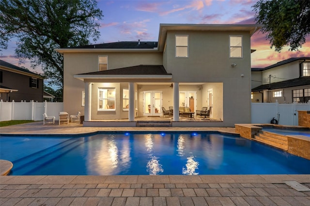 4515 W Leona St, Tampa, FL 33629 - back of house at dusk featuring a patio area, stucco siding, a fenced backyard, french doors, and a pool with connected hot tub