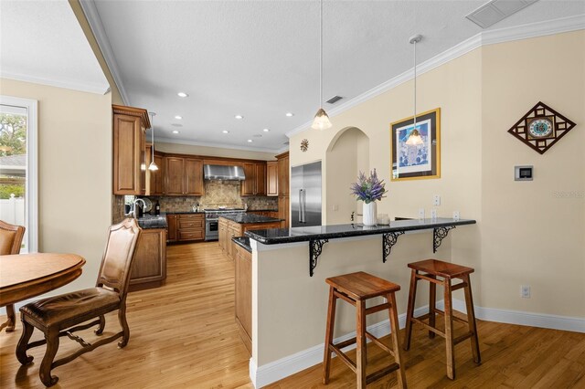 4515 W Leona St, Tampa, FL 33629 - kitchen with premium appliances, wall chimney exhaust hood, light wood-type flooring, crown molding, and a breakfast bar