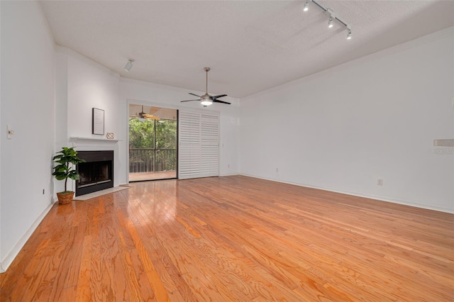 3044 Red Oak Ct Unit 204, Palm Harbor, FL 34684 - unfurnished living room featuring a fireplace with flush hearth, rail lighting, light wood-style floors, a ceiling fan, and baseboards