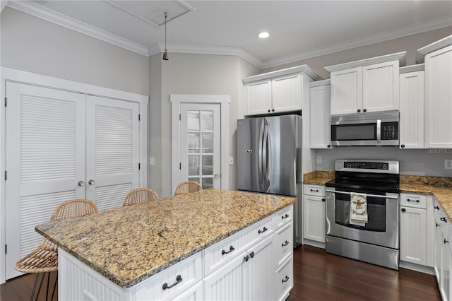 3620 W San Pedro St, Tampa, FL 33629 - kitchen featuring appliances with stainless steel finishes, dark wood-style floors, a center island, ornamental molding, and light stone counters