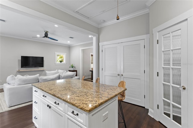 3620 W San Pedro St, Tampa, FL 33629 - kitchen featuring dark wood-style floors, ornamental molding, light stone counters, a breakfast bar, and a center island