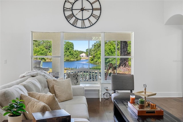 living room with a water view, wood finished floors, and a towering ceiling