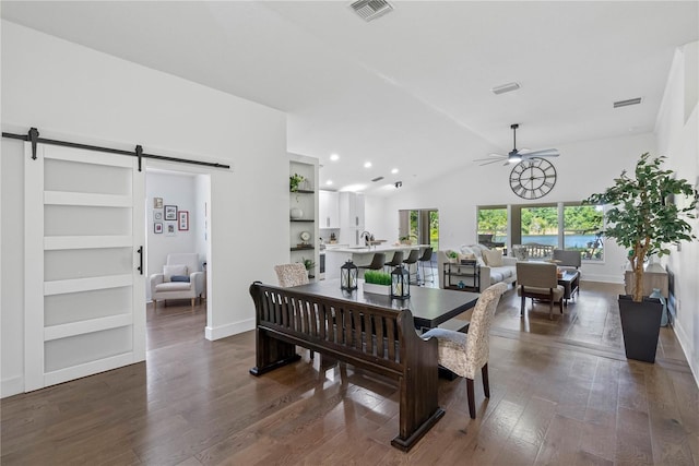 dining space featuring a barn door, a ceiling fan, lofted ceiling, dark wood-style floors, and baseboards