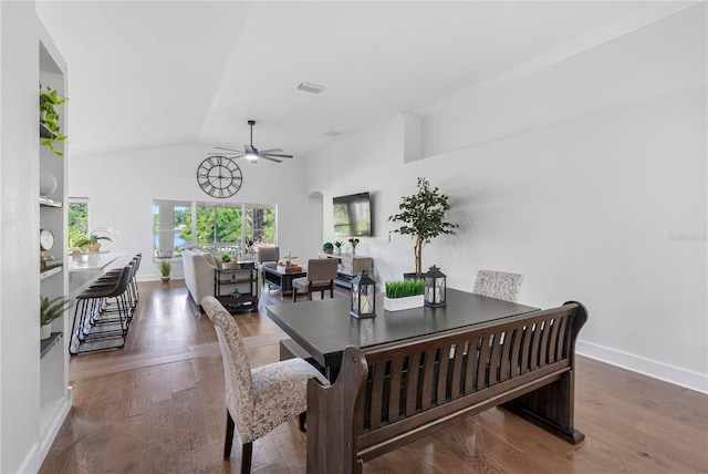 dining area with a ceiling fan, vaulted ceiling, baseboards, and wood finished floors