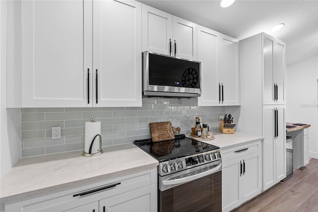 kitchen featuring appliances with stainless steel finishes, light wood-type flooring, and white cabinets