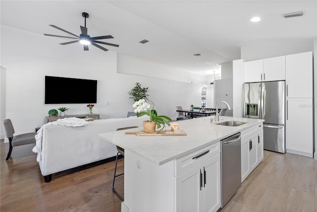 kitchen with a sink, appliances with stainless steel finishes, a center island with sink, open floor plan, and recessed lighting