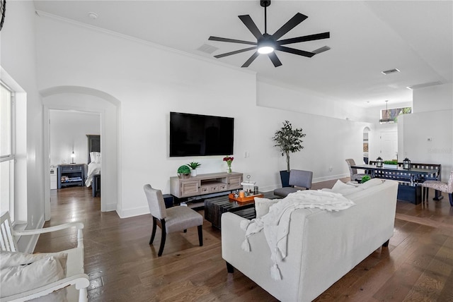 living room with arched walkways, a ceiling fan, dark wood finished floors, baseboards, and crown molding