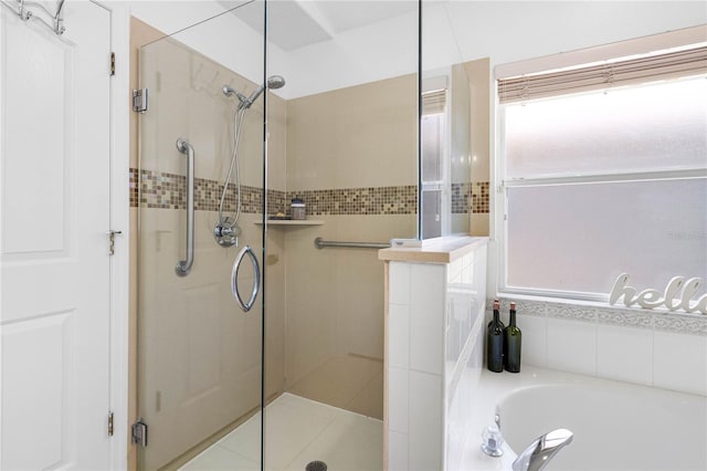 full bathroom featuring a shower stall, a garden tub, and plenty of natural light