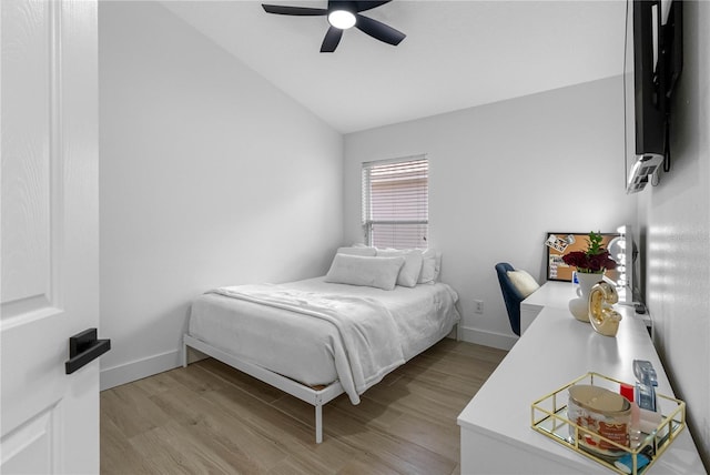 bedroom featuring vaulted ceiling, light wood-style floors, baseboards, and ceiling fan