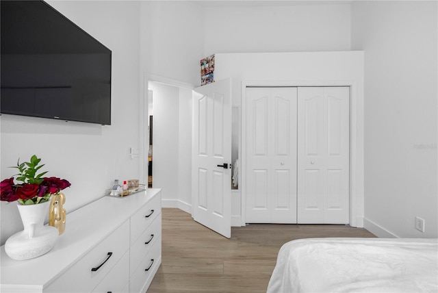 bedroom featuring light wood-type flooring, baseboards, and a closet