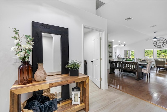 hallway featuring vaulted ceiling and light wood-style floors