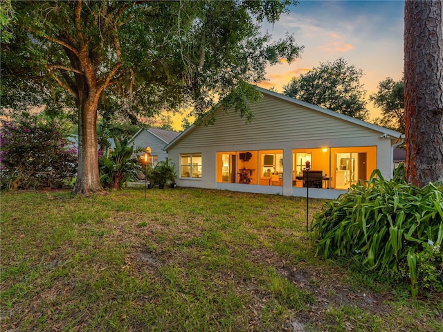 back of property at dusk with a lawn