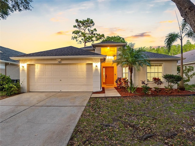 view of front of home with stucco siding, a garage, and driveway
