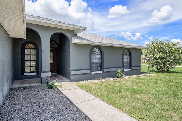 31645 Bugle Ln, Wesley Chapel, FL 33543 - property entrance with stucco siding, a yard, and a shingled roof