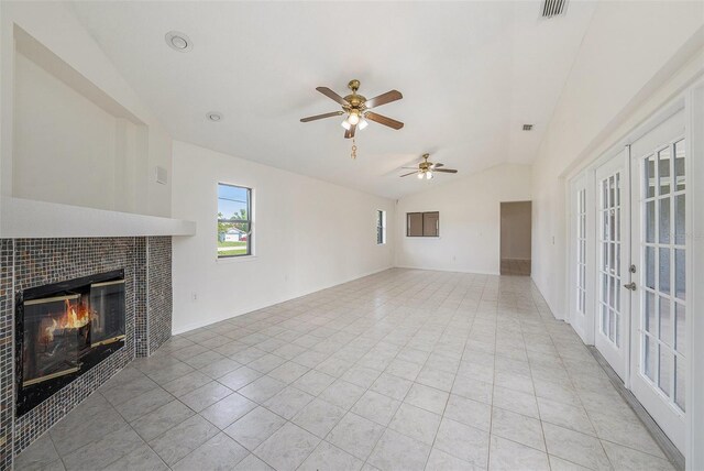 31645 Bugle Ln, Wesley Chapel, FL 33543 - unfurnished living room with lofted ceiling, french doors, a tiled fireplace, light tile patterned floors, and a ceiling fan