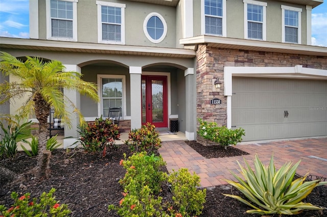 11550 Lake Lucaya Dr, Riverview, FL 33579 - doorway to property with stone siding, stucco siding, a garage, and a porch