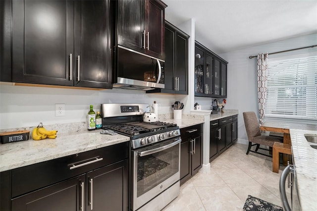 11550 Lake Lucaya Dr, Riverview, FL 33579 - kitchen with appliances with stainless steel finishes, light tile patterned floors, dark cabinets, and light stone counters