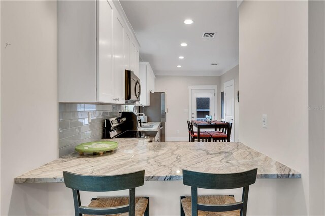 340 6th St E, Bradenton, FL 34208 - kitchen featuring stainless steel appliances, tasteful backsplash, recessed lighting, white cabinetry, and a peninsula
