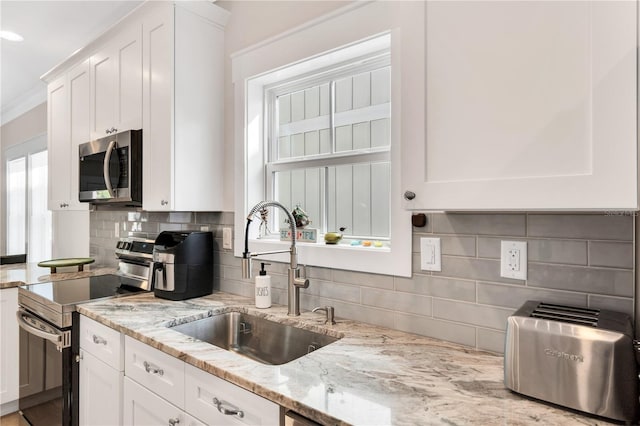 340 6th St E, Bradenton, FL 34208 - kitchen featuring appliances with stainless steel finishes, a sink, white cabinetry, and tasteful backsplash