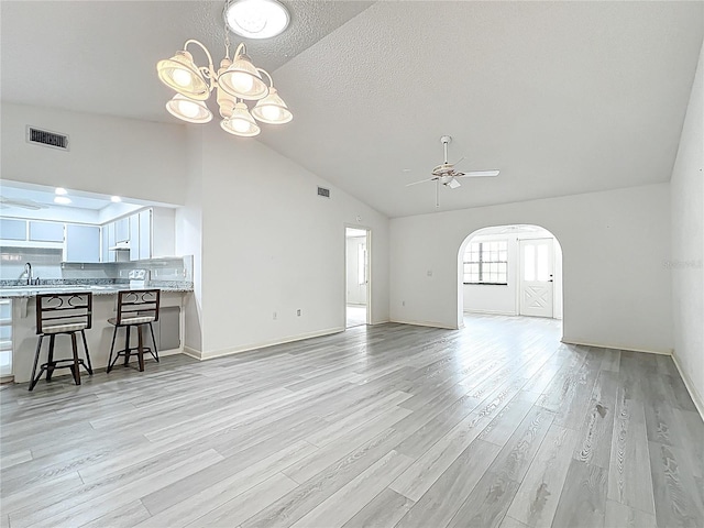 3328 S Whitechappel Pt, Inverness, FL 34452 - unfurnished living room with vaulted ceiling, a sink, ceiling fan, arched walkways, and a chandelier