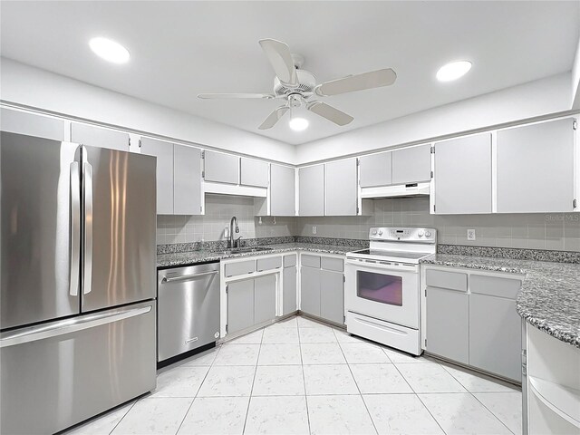 3328 S Whitechappel Pt, Inverness, FL 34452 - kitchen with stainless steel appliances, under cabinet range hood, light stone countertops, a sink, and ceiling fan