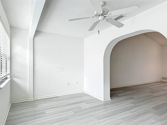 3328 S Whitechappel Pt, Inverness, FL 34452 - empty room featuring arched walkways, light wood-type flooring, a textured ceiling, ceiling fan, and baseboards