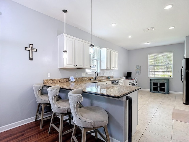 3512 Gerrads Cross Ct, Land O Lakes, FL 34638 - kitchen featuring light stone countertops, a peninsula, plenty of natural light, white cabinets, and recessed lighting