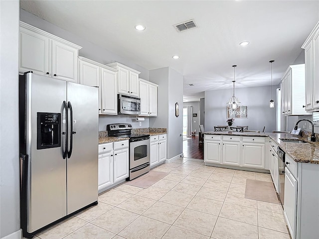 3512 Gerrads Cross Ct, Land O Lakes, FL 34638 - kitchen with stainless steel appliances, a peninsula, dark stone countertops, light tile patterned floors, and white cabinetry